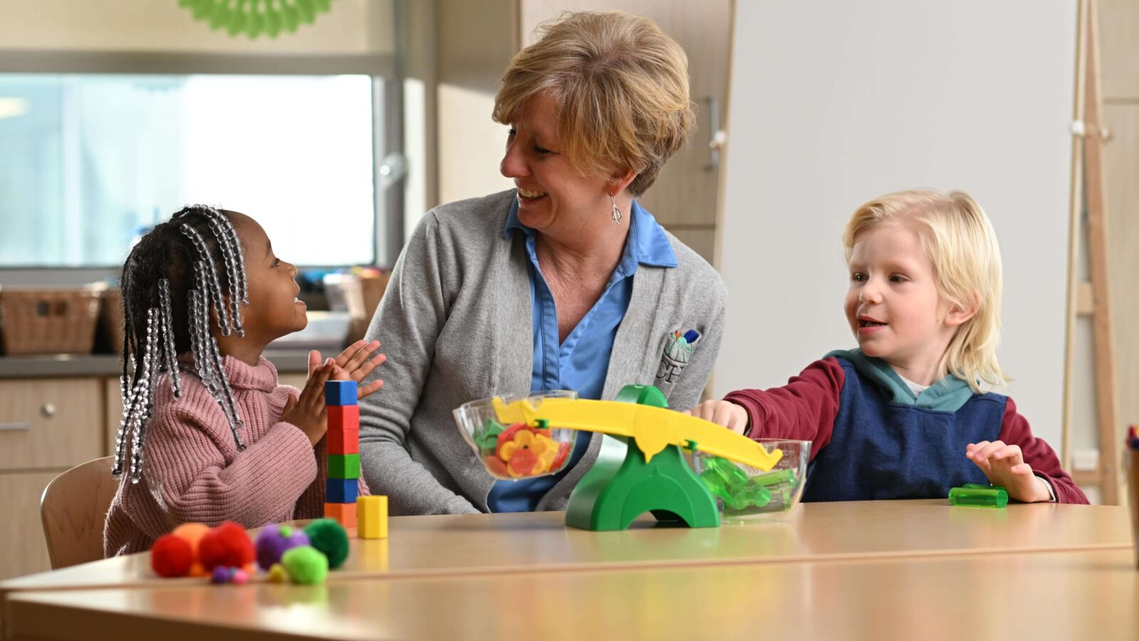 Teacher and two kids at table playing with toys